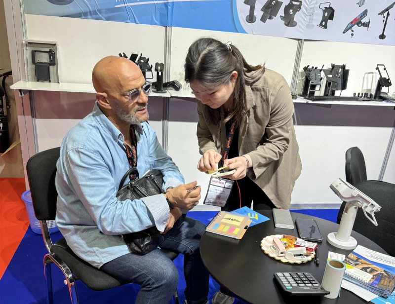 Haiyuan team discussing POS mounting products with a visitor at an international payment exhibition